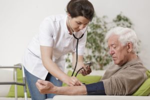 48766091 - young nurse taking old man's blood pressure